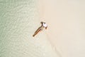 Summer holiday fashion concept - tanning girl wearing sun hat at the beach on a white sand shot from above.Top view from drone.