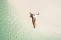 Summer holiday fashion concept - tanning girl wearing sun hat at the beach on a white sand shot from above.Top view from drone. Royalty Free Stock Photo