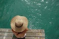 Summer holiday fashion idea: A sunbathing woman in a sun hat on a wooden pier, viewed from above