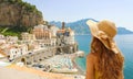 Summer holiday in Italy. Back view of young woman with straw hat and yellow dress with Atrani village on the background, Amalfi