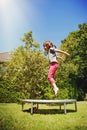 Summer holiday, rest, happy childhood concept. Little cute child girl having fun outdoors and she jumping on a trampoline Royalty Free Stock Photo