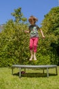 Summer holiday and rest outdoors. Happy little cute child girl having fun and jumping on a trampoline in sun rays Royalty Free Stock Photo