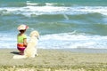 Young Little Girl And Golden Retriever Dog Sitting On The Beach. Royalty Free Stock Photo