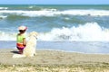 Young Little Girl And Golden Retriever Dog Sitting On The Beach. Royalty Free Stock Photo