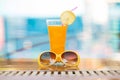Summer holiday tropical concept. Fresh orange juice and sunglasses on border of a swimming pool Royalty Free Stock Photo
