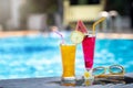 Summer holiday tropical concept. Fresh orange juice and watermelon juice on border of a swimming pool Royalty Free Stock Photo