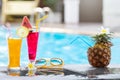 Summer holiday tropical concept. Fresh orange juice and watermelon juice and pineapple on border of a swimming pool Royalty Free Stock Photo