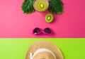 Summer holiday vacation concept with beach hat, kiwi fruit and tropical leaves on pink background. Top view from above Royalty Free Stock Photo