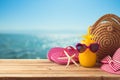 Summer holiday vacation  concept with pineapple juice, beach fashion bag and flip flops on wooden table over sea beach background Royalty Free Stock Photo