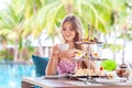 Woman drink coffee or tea with desserts at restaurant with palm trees
