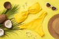 Summer holidays concept. Top view photo of yellow bikini hat stylish sunglasses shell bracelet earrings coconuts and palm leaves Royalty Free Stock Photo