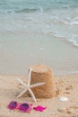 Summer holidays concept. Vertical banner mockup. Pink sunglasses, sea star and a sand castle on the sand of a beach Royalty Free Stock Photo