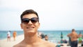 Happy smiling handsome young man in sunglasses on beach Royalty Free Stock Photo