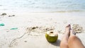 Coconut and legs on the white beach