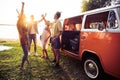 Summer holidays, road trip, vacation, travel and people concept - smiling young hippie friends having fun over minivan Royalty Free Stock Photo