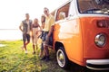 Summer holidays, road trip, vacation, travel and people concept - smiling young hippie friends having fun over minivan Royalty Free Stock Photo