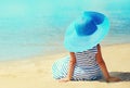 Summer holidays and vacation concept - little girl in striped dress, straw hat enjoying sitting on sand beach Royalty Free Stock Photo
