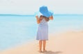 Summer holidays, vacation - little girl child wearing a straw hat, striped dress relaxing on beach near sea Royalty Free Stock Photo