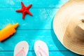 Summer holidays and vacation travel concept. Sunscreen lotion bottle, straw hat, flip flops and red starfish on pastel blue Royalty Free Stock Photo