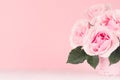 Summer home interior in romance style - gentle pink roses bouquet on white wood background and pink wall, closeup, copy space. Royalty Free Stock Photo