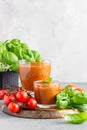 Summer homemade cold tomato cream soup in glass. Traditional Spanish soup gazpacho with basil. Grey concrete background Royalty Free Stock Photo