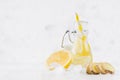 Summer homemade drink - infused lemon water with ice cubes, ginger, slices, soda, straw in yoke bottle in soft light white. Royalty Free Stock Photo