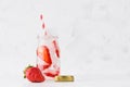 Summer homemade drink - infused strawberry water with sliced berry, ice cubes, soda, cap, straw in soft light white interior.