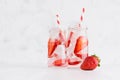 Summer homemade drinks - infused strawberry water with sliced berry, ice cubes, soda, straw in soft light white interior. Royalty Free Stock Photo