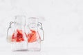 Summer homemade drinks - infused strawberry water with sliced berry, soda in yoke bottles in soft light white interior, copy space