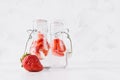 Summer homemade drinks - infused strawberry water with sliced berry, soda in yoke bottles in soft light white interior, copy space