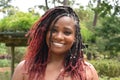 A portrait of a radiant and spectacular woman of color with a rare, braided hair style of red dye at the ends