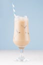 Summer ice coffee cocktail with ice cubes and striped straw on soft light blue wall and white wooden table, vertical. Royalty Free Stock Photo