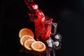 Hibiscus cold tea pouring into glass with ice, lemon and mint isolated on black background Royalty Free Stock Photo