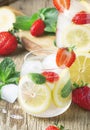 Summer iced lemonade with strawberries, lemon, mint and soda, vintage wood background, selective focus Royalty Free Stock Photo