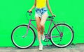 Summer image of legs of beautiful young woman in shorts posing with bicycle in the city on green background Royalty Free Stock Photo
