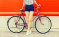 Summer image of legs of beautiful young woman in shorts posing with bicycle in the city on red background Royalty Free Stock Photo