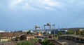 Summer industrial landscape: blue sky, railway with trains and freestanding wagons, loading cranes, old and new industrial buildin Royalty Free Stock Photo