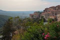 Summer landscape with red clay tile roofs of small houses on a hillside with parks, flowers and mountains in the background