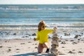 Summer kid meditation. Kid with balanced stone pebble pyramid on the beach. Child play with zen stones on the sea beach Royalty Free Stock Photo