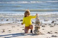 Summer kid meditation. Child boy with balanced stone pebble pyramid on the beach. Child play with zen stones on the sea Royalty Free Stock Photo