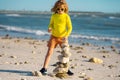 Summer kid meditation. Child play with pyramid stones balance on the sand of the beach. Kid with stack of stones on sand Royalty Free Stock Photo