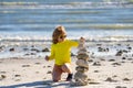 Summer kid meditation. Child play with pyramid stones balance on the sand of the beach. Kid with stack of stones on sand Royalty Free Stock Photo