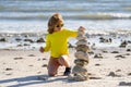 Summer kid meditation. Little child playing with stones on the beach. Child play with pyramid of stones on the beach Royalty Free Stock Photo