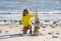 Summer kid meditation. Little kid play with pyramid stones balance on the sand of the beach. Kid with stack of stones on Royalty Free Stock Photo