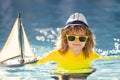 Summer kids portrait. Child playing with toy boat in sea. Happy holiday by the sea. Little sailor. Kid dreaming about Royalty Free Stock Photo