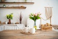 Summer kitchen interior in rustic style. Bright kitchen with a wooden table. Spring flowers and bread in a basket on the table in Royalty Free Stock Photo