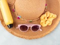 Summer lady straw hat, yellow sun protection spray and sunglasses on turquoise stone background.