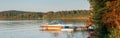 Summer on lake cottage. Small yacht boat by wooden dock pier on lake at sunset. Canadian Ontario Muskoka countryside travel Royalty Free Stock Photo