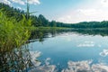 Summer lake landscape with beautiful blue sky, green forest and sunlight. Reflection of the bright sky in the lake Royalty Free Stock Photo