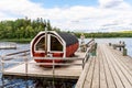 Summer lake nature landscape view of a traditional Scandinavian water floating red wooden sauna spa next to a jetty. Royalty Free Stock Photo